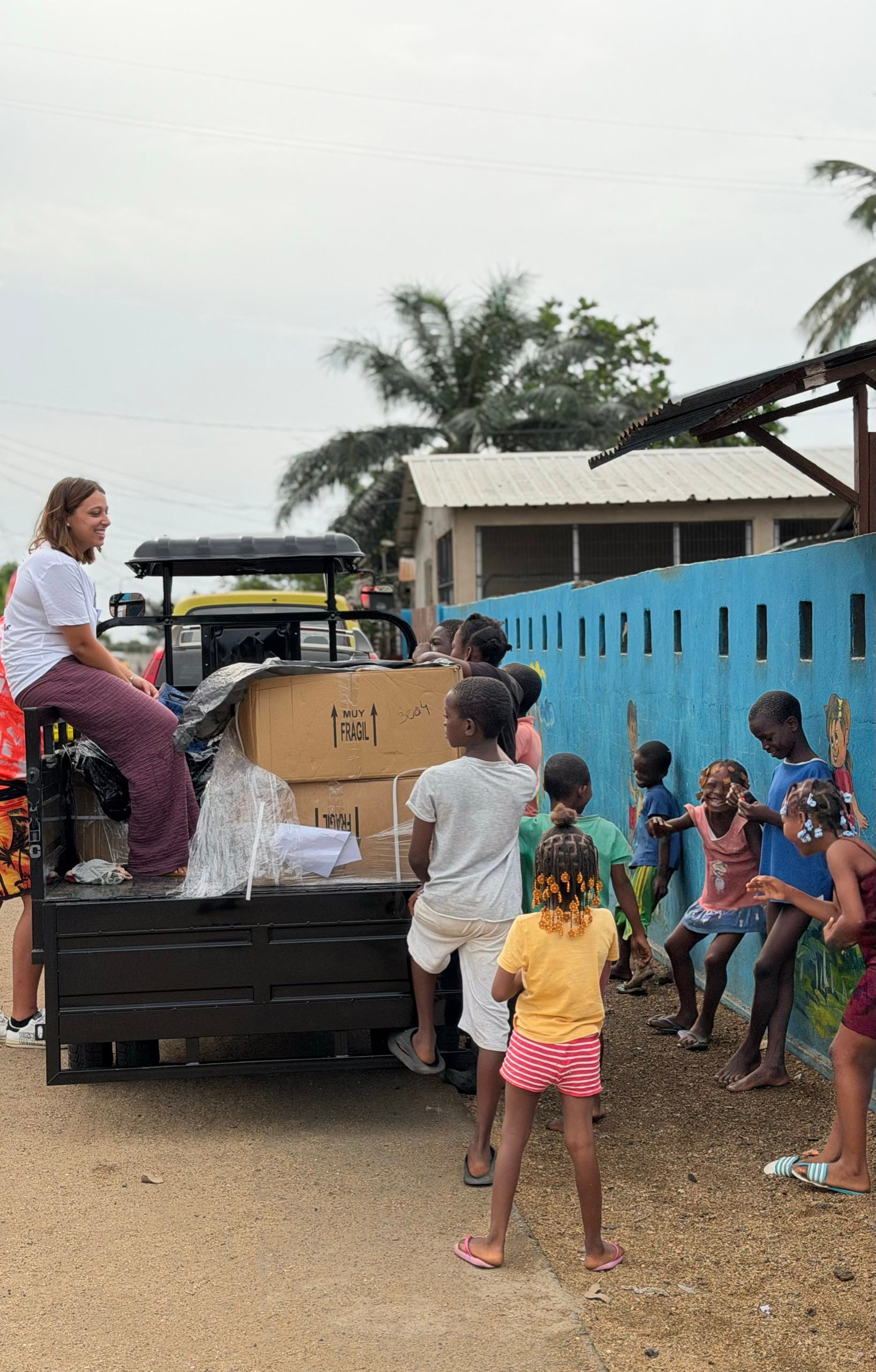 Voluntários a descarregar caixas junto de crianças em São Tomé.